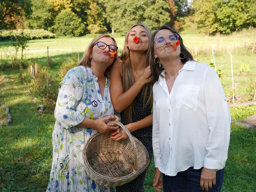 Trzy uśmiechnięte kobiety pozują do zdjęcia w ogrodzie